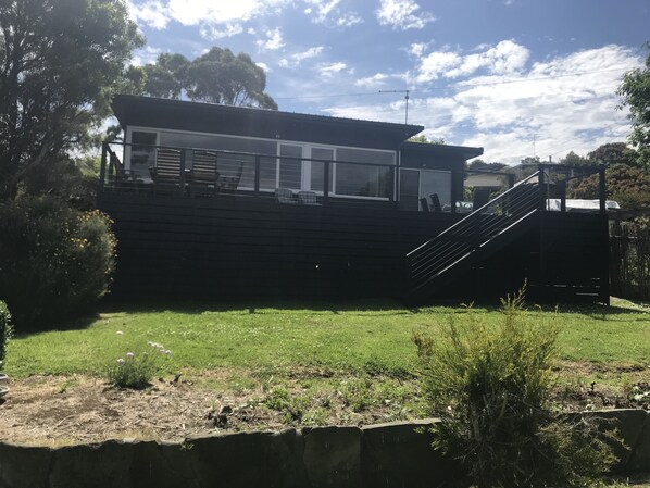 Una casa moderna con una amplia terraza, una escalera y un césped bien cuidado.