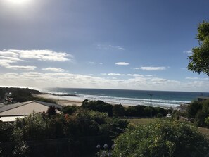 A coastal view with a beach, ocean, and a clear sky.