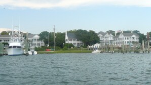 A waterfront property with a dock, boats, and a row of white houses with green lawns. - Ocean-side condominium with pool. Fully-equipped for relaxed vacationing. (Atlantic Beach)