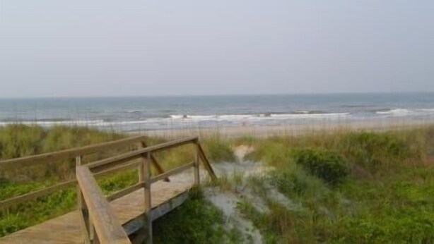 A wooden boardwalk leading to a beach with ocean views. - Ocean-side condominium with pool. Fully-equipped for relaxed vacationing. (Atlantic Beach)