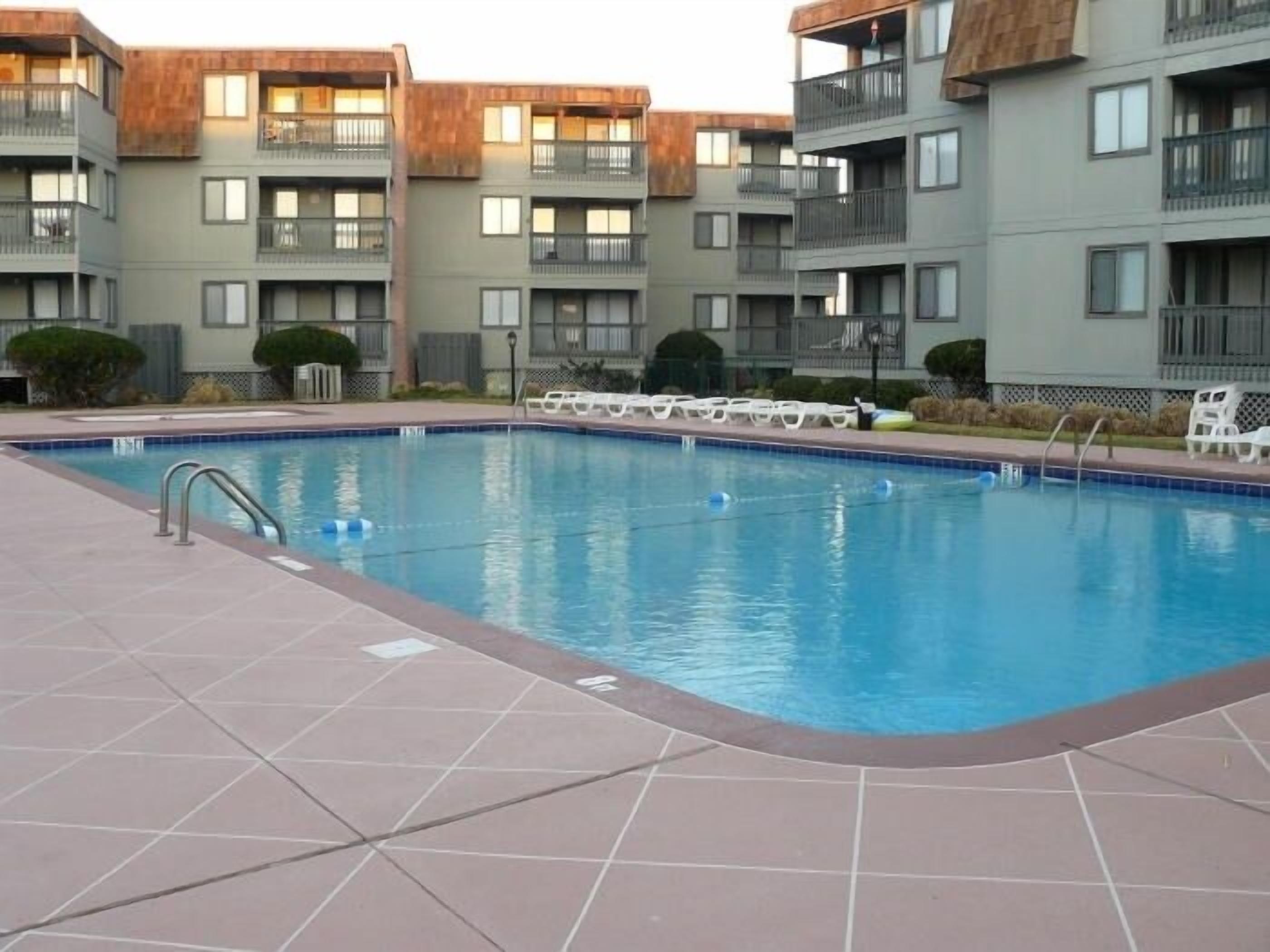 A swimming pool with tiled deck, surrounded by apartment buildings with balconies.