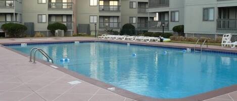 A swimming pool with tiled deck, surrounded by apartment buildings with balconies.
