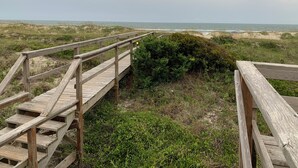 A wooden boardwalk leading to a beach with dunes and a cloudy sky. - Ocean-side condominium with pool. Fully-equipped for relaxed vacationing. (Atlantic Beach)