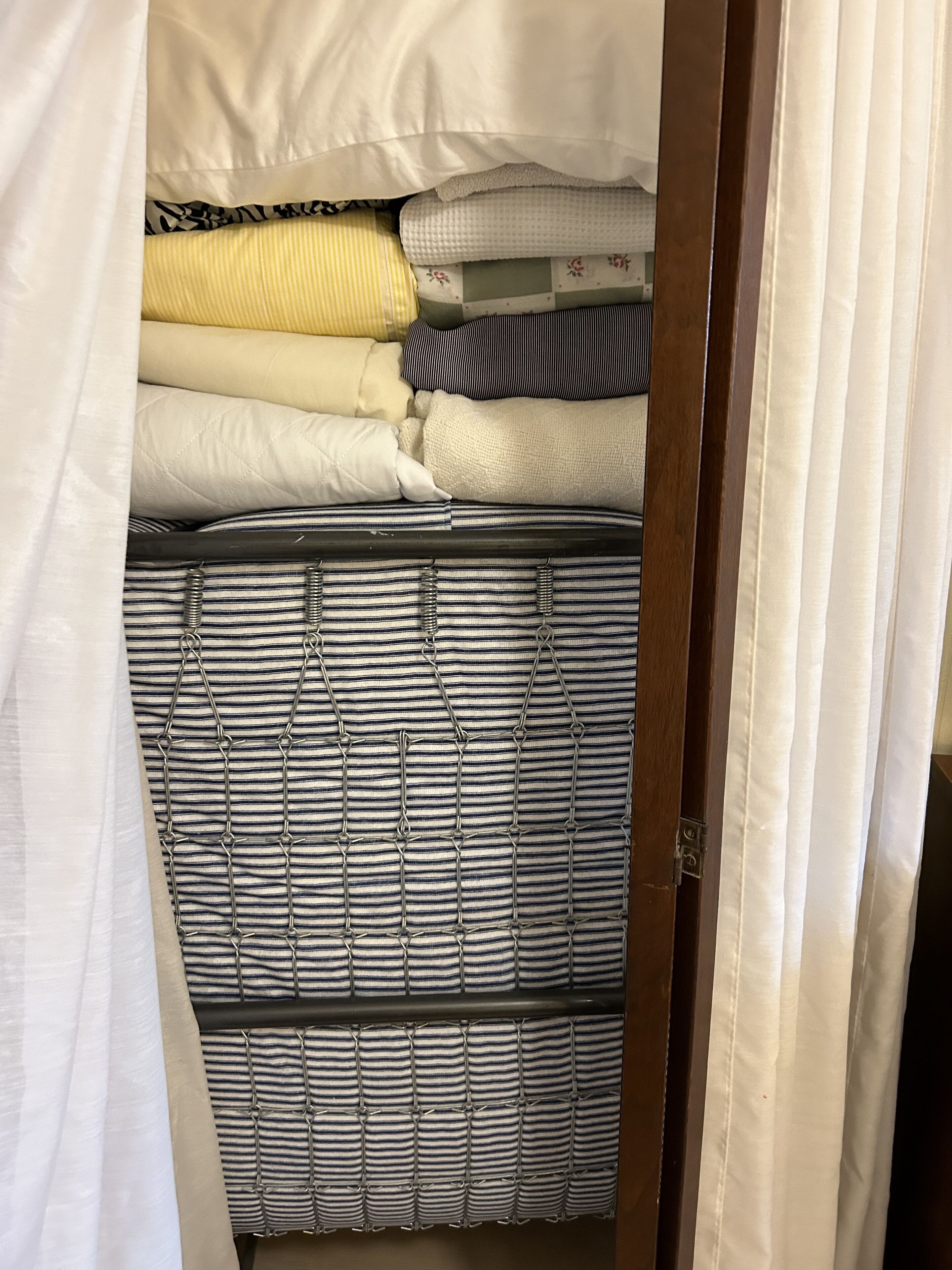 A bed with striped bedding and a metal headboard.