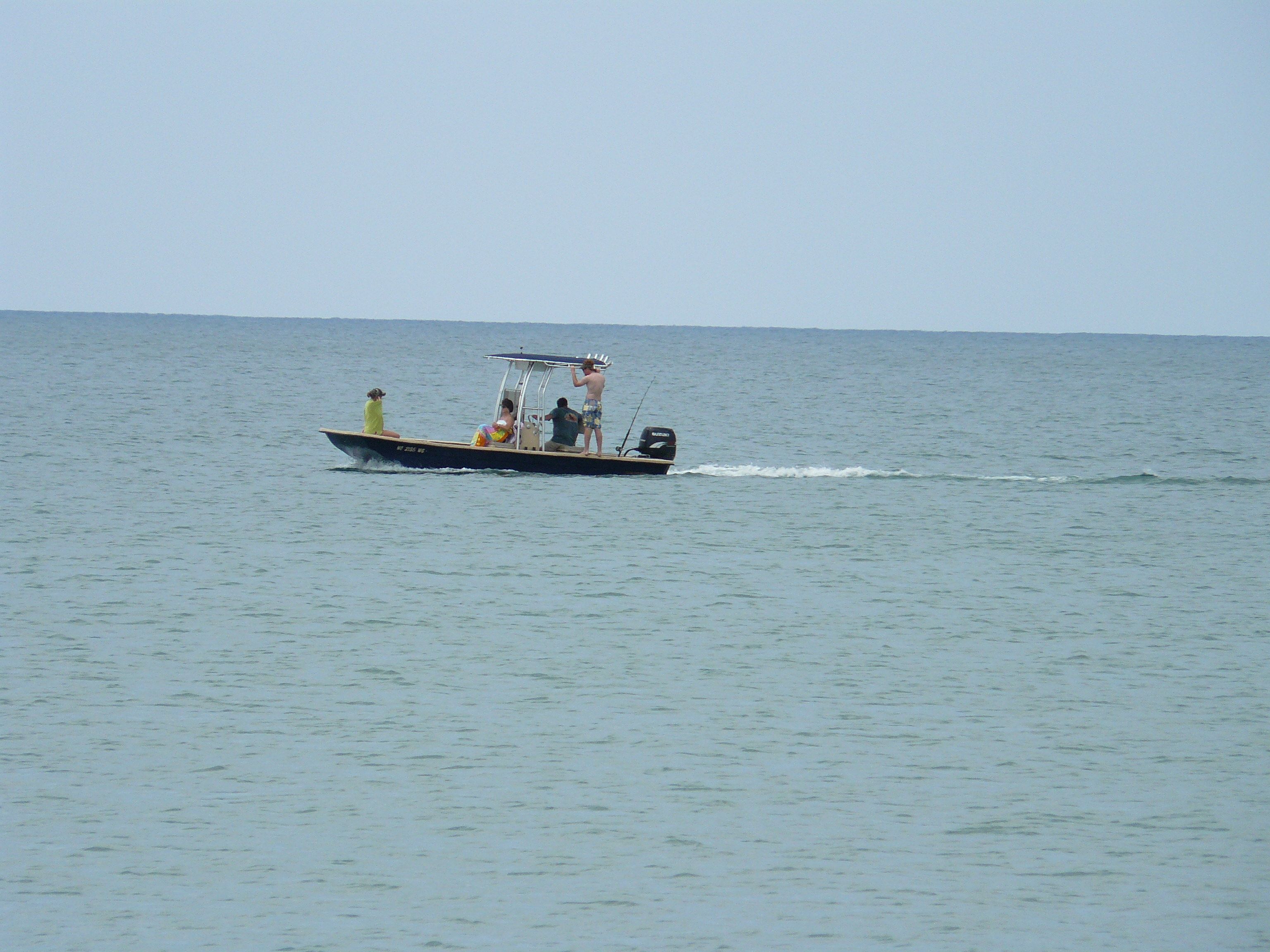 A small motorboat with three people on board, moving across a calm sea.