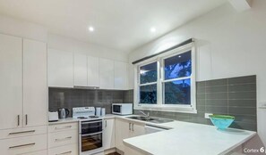 A modern kitchen with white cabinets, a microwave, a toaster, and a sink.