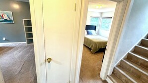 A bedroom with a bed, a window, and a staircase.