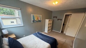 Une chambre à coucher comprenant un lit, une fenêtre, un tableau, une armoire et une étagère.