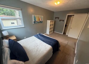 Une chambre à coucher comprenant un lit, une fenêtre, un tableau, une armoire et une étagère.