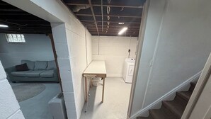 A basement with a couch, a table, and a washing machine.