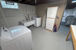 Une buanderie équipée d’un lave-linge, d’un sèche-linge, d’un évier et d’un meuble de rangement.