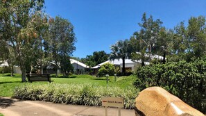 Stroll along the well-maintained pathway to the beach access point, lined with neatly trimmed hedges and palm trees.