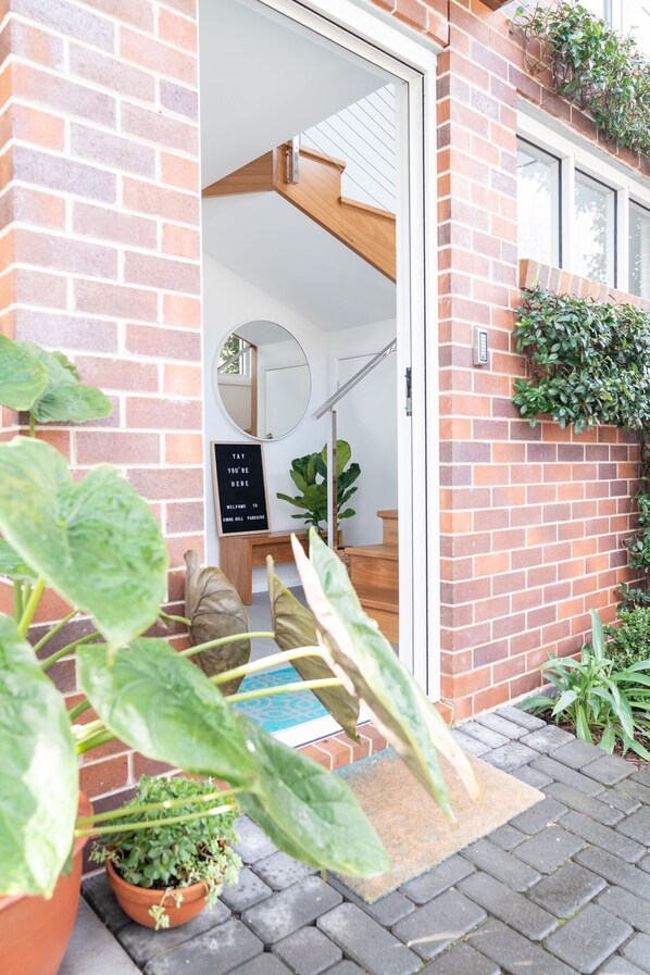 A brick building with a wooden staircase leading to a room with a mirror and a welcome sign.