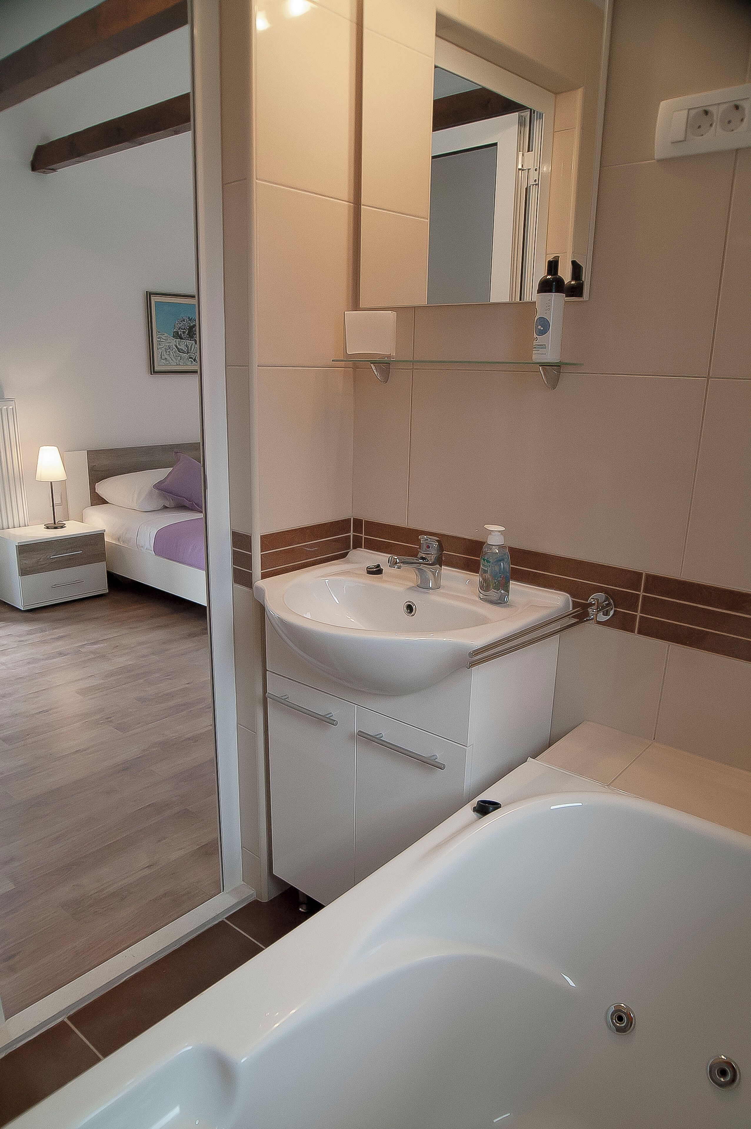 A modern bathroom with a bathtub, a sink, and a mirror.