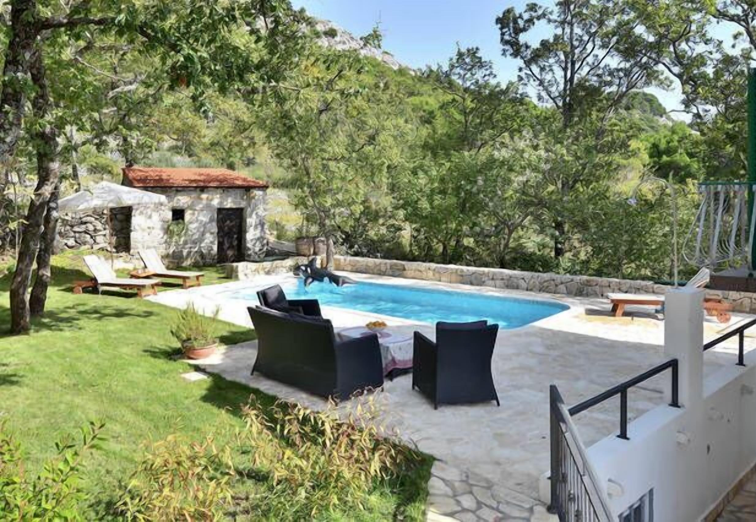 Un espace piscine avec des chaises longues et, en arrière-plan, un bâtiment en pierre.