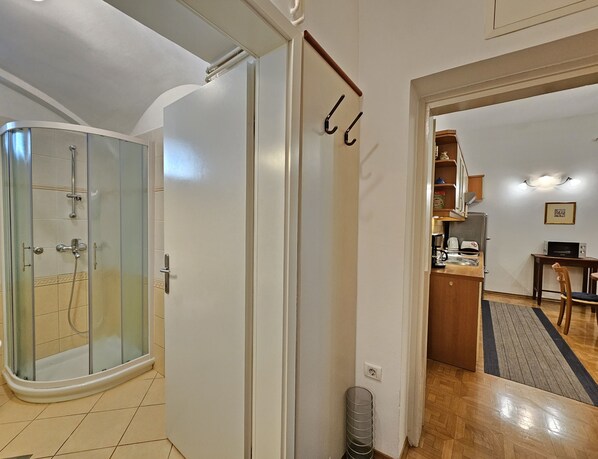 Un baño moderno con cabina de ducha de vidrio, una puerta blanca y un perchero visible.