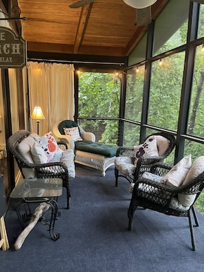 Una habitación acogedora con muebles de mimbre, un sofá verde y vistas al exterior.