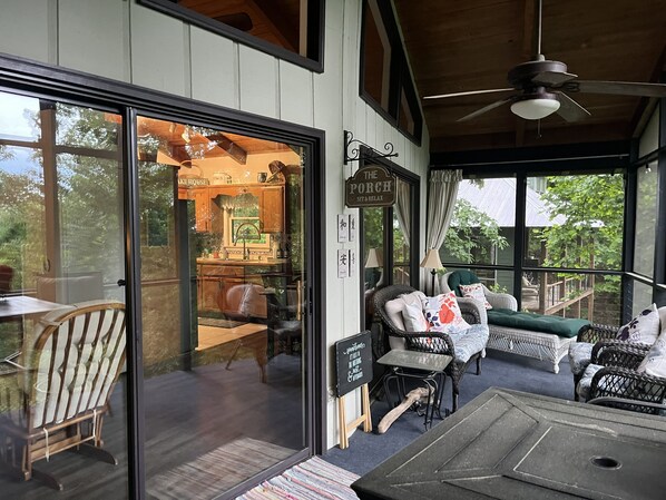 A cozy porch with wicker furniture, a ceiling fan, and a view of the garden.