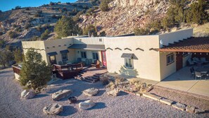A modern building with a patio area, outdoor seating, and a view of a rocky hillside.