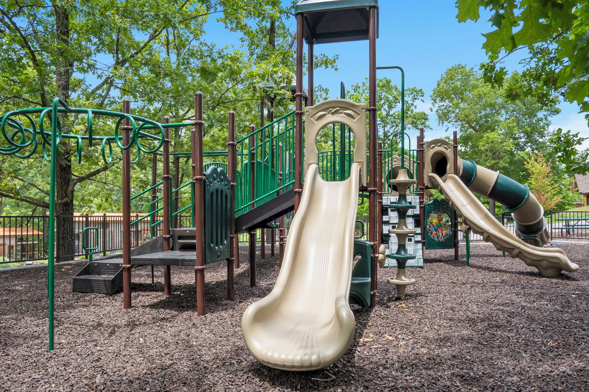 Ein Spielplatz mit Rutsche, Klettergerüsten und einem überdachten Spielbereich.