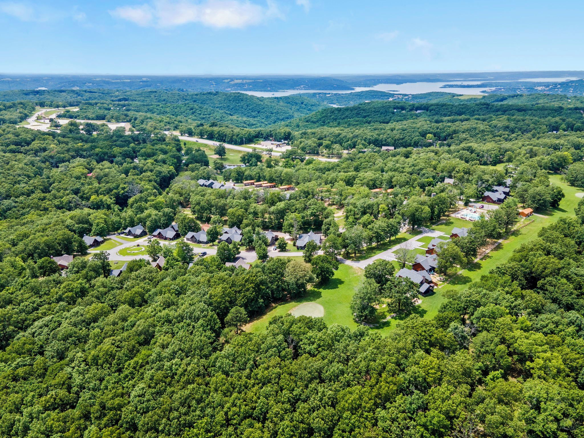 An aerial view of a residential area with multiple houses, roads, and a large body of water in the distance.