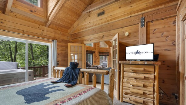 Una stanza in baita con un letto, una televisione e vista sull'esterno.