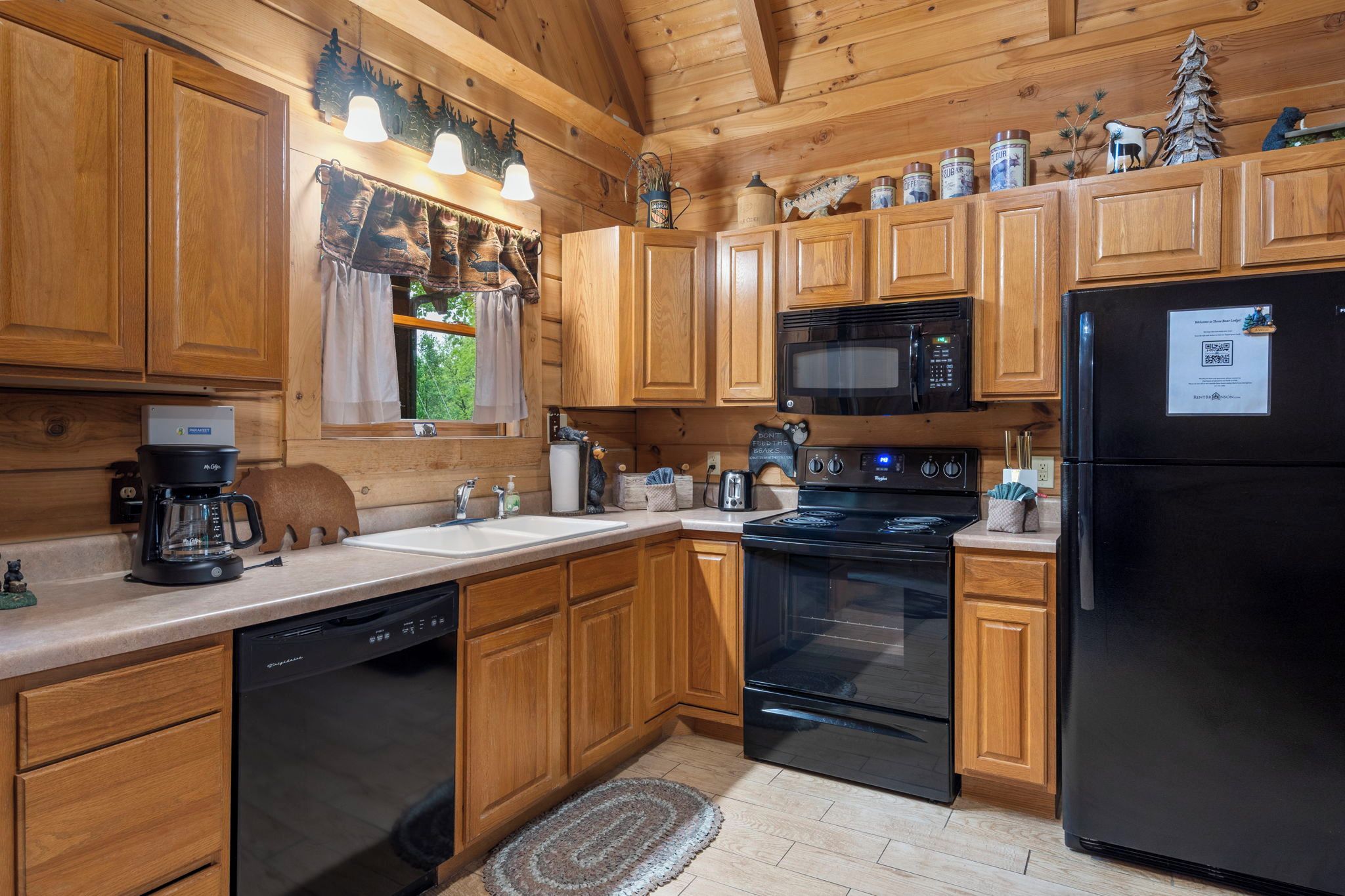 Una cocina con armarios de madera, un refrigerador negro, una estufa y un microondas.