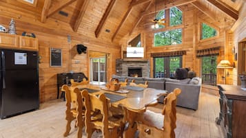 Eine geräumige Holzhütte mit Essbereich, Kamin und gemütlichem Wohnzimmer mit Sofa und Kamin.