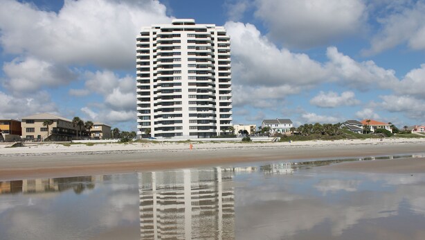 A high-rise hotel with multiple balconies, a beach in the foreground, and a clear sky. - 7th Floor End Unit - Right on the Beach (Daytona Beach)