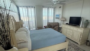A bedroom with a bed, a television, a ceiling fan, and a window with blinds. - 7th Floor End Unit - Right on the Beach (Daytona Beach)