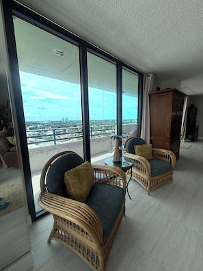 A spacious balcony with wicker furniture, a view of the cityscape, and a large wooden cabinet.