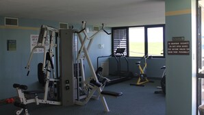 A gym with various exercise equipment, including a weight machine, treadmills, and stationary bikes. - 7th Floor End Unit - Right on the Beach (Daytona Beach)