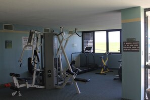 Una palestra con diverse attrezzature per l'allenamento, tra cui macchinari per pesi, tapis roulant e cyclette.