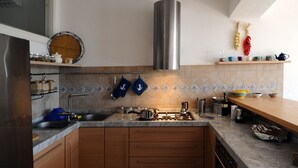 Une cuisine moderne avec des meubles en bois, une hotte de cuisinière en acier inoxydable et un dosseret carrelé.