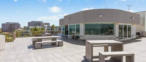 A modern building with large windows and a flat roof terrace with concrete benches.