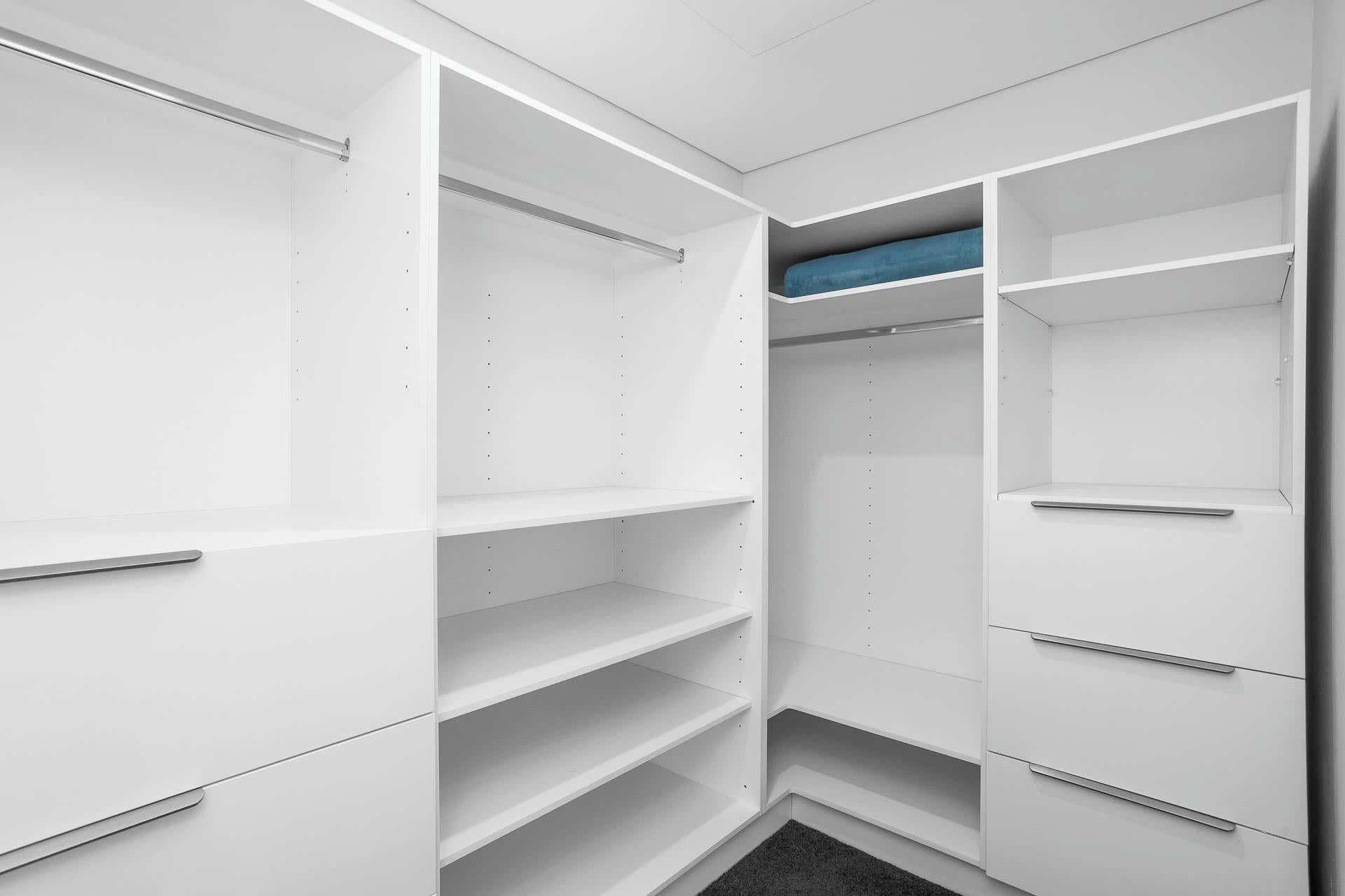 A white walk-in closet with open doors, revealing shelves and hanging space.