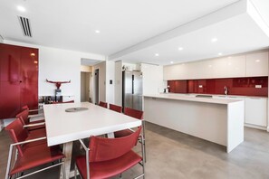 A modern kitchen with white cabinets, a stainless steel refrigerator, and a red accent wall.