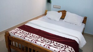 Un dormitorio con una cama de madera, ropa de cama blanca y una colcha roja y blanca estampada.