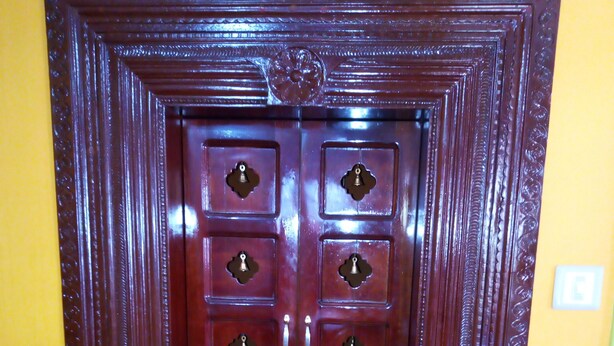 Una puerta doble de madera con cerradura central y detalles decorativos.