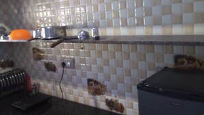 Una cocina con salpicadero de azulejos, encimera negra y refrigerador.