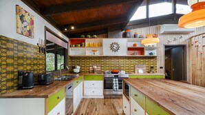 Una cocina moderna con encimera de madera, armarios verdes y blancos, y salpicadero con un motivo repetido.