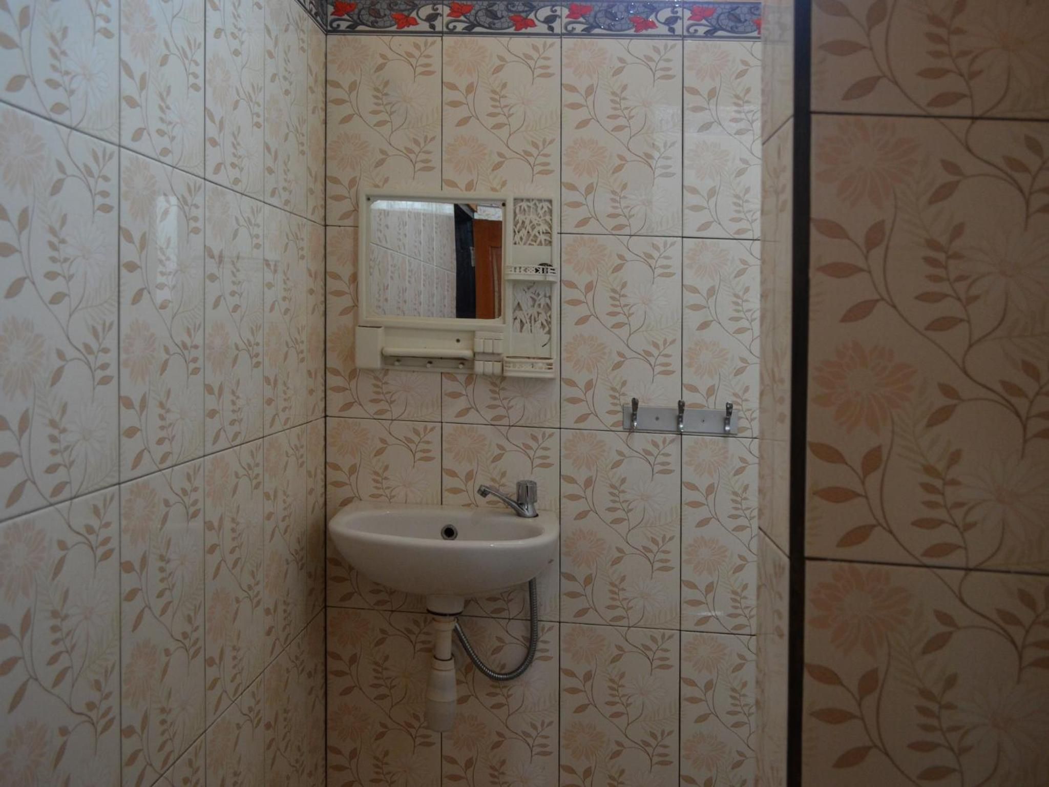 Un baño con lavamanos, espejo y azulejos decorativos.
