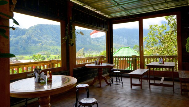 A wooden deck with tables and chairs, overlooking a lush valley and mountains. - Dajan Buyan Homestay (Bedugul)