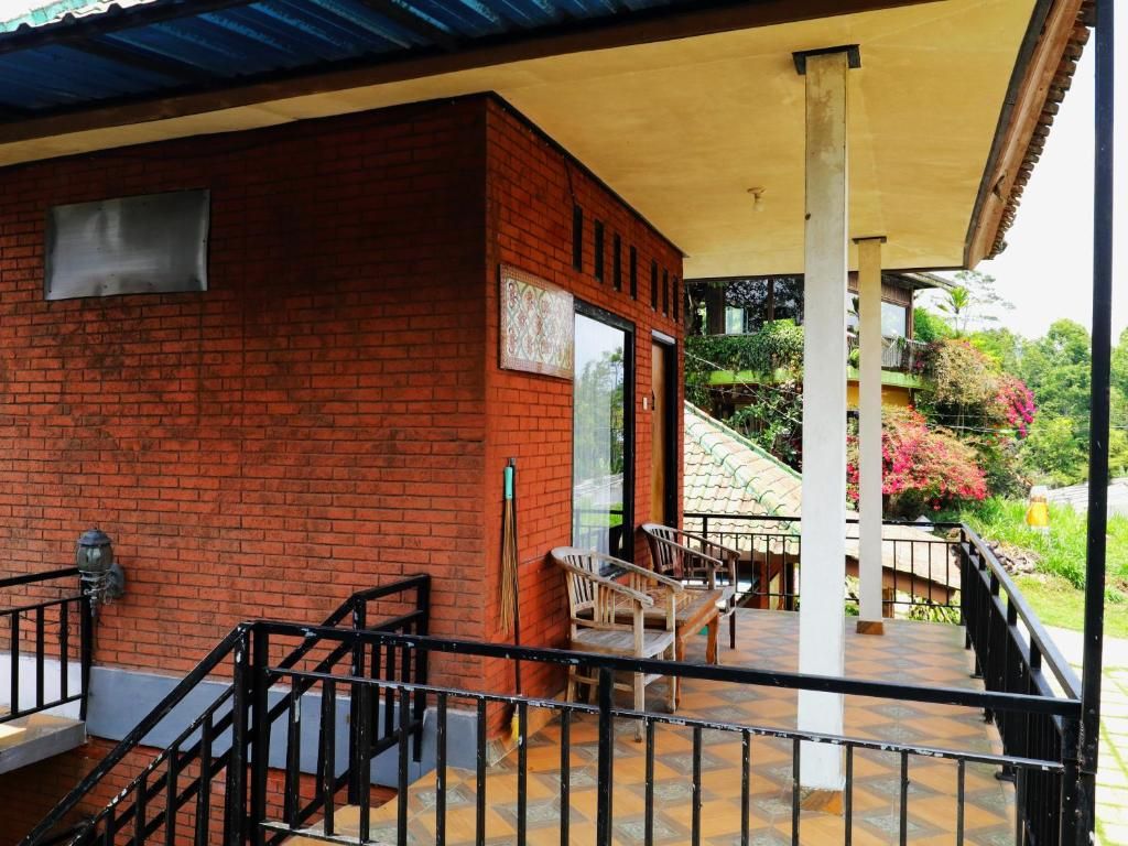 A covered outdoor area with a brick wall, a staircase, and a seating area with chairs.
