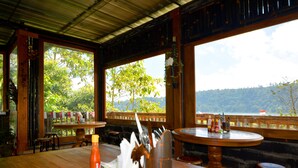 A wooden table with a bottle of ketchup, a napkin, and a glass. - Dajan Buyan Homestay (Bedugul)