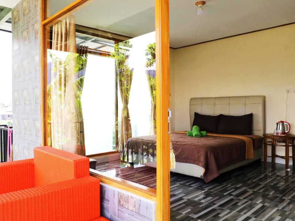 A hotel room with a bed, a small table, and a window with curtains.