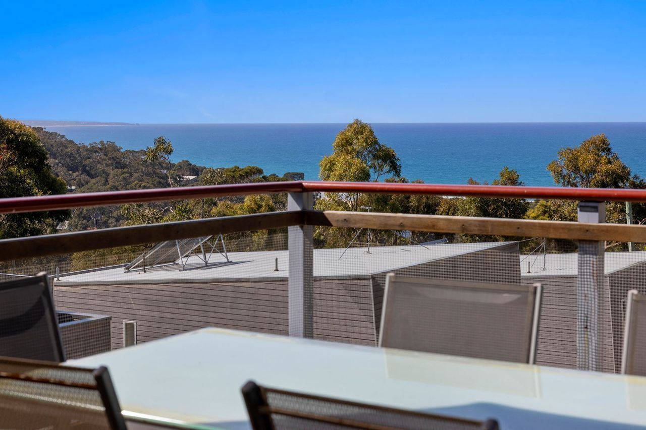 A terrace with a view of the ocean, outdoor seating, and a railing.