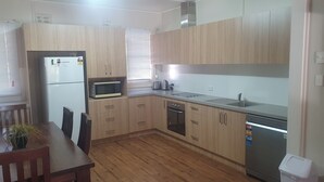 Cocina compacta con armarios de madera, microondas, lavavajillas y refrigerador.