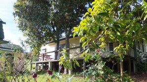 Un edificio de dos plantas con balcón, rodeado de exuberante vegetación y árboles.