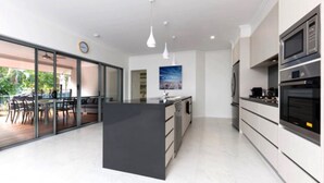 Ett modernt kök med en central köksö, inbyggda vitvaror och en matplats med utsikt.